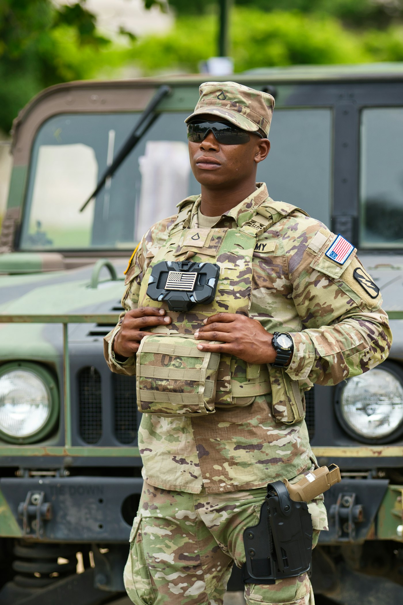 A U.S. Army soldier holding a handheld device beside a military vehicle