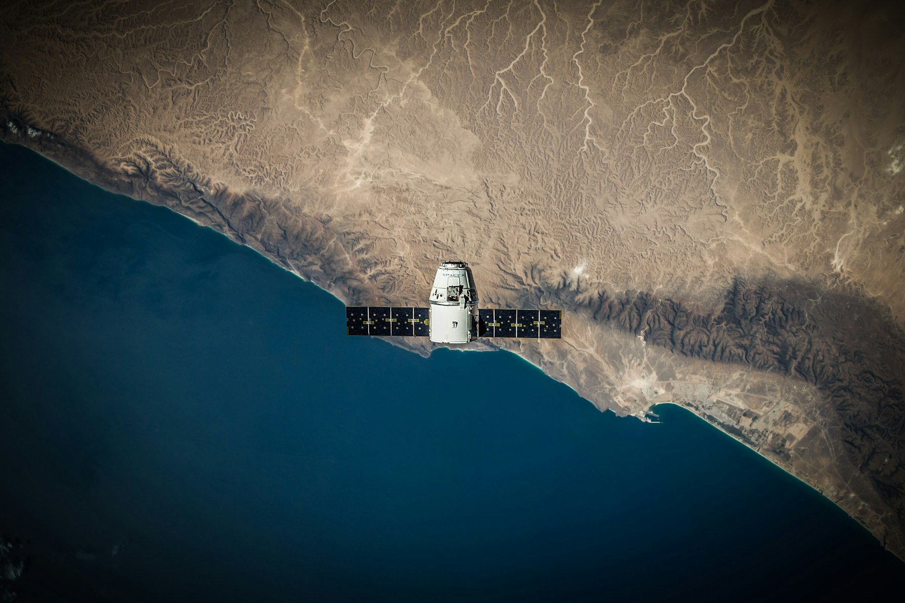 A spacecraft in orbit above a desert coastline